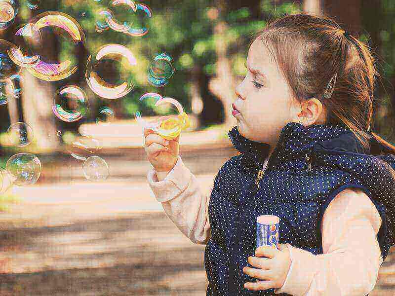 Slika deklice, ki piha milnate mehurčke